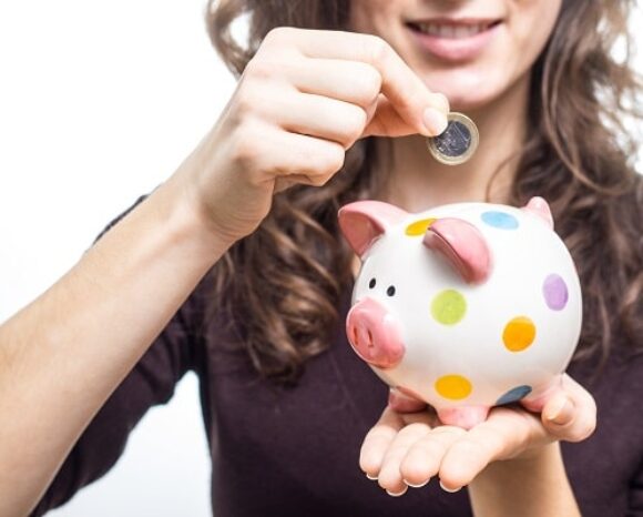 Vertreterin der Generation Z wirft Geldmünze in Sparschwein