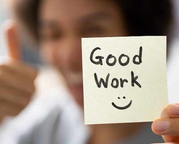 Frau hält Zettel hoch, auf dem steht "Good work"