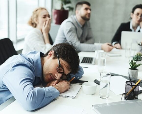 Mann schläft bei langweiligem Meeting auf dem Tisch