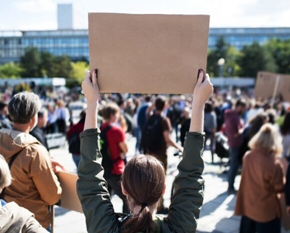 Frau hält im Streik Pappschild hoch