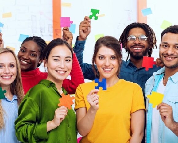 Menschen aus verschiedenen Herkunftsländern halten Puzzleteile hoch