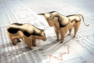 Zwei goldene Figuren – ein Bär und ein Bulle – stehen auf einer Finanzzeitung mit Börsendaten und Charts. Der Bulle wirkt stark und angriffslustig und symbolisiert einen Bullenmarkt, während der Bär zurückhaltender wirkt und einen Bärenmarkt repräsentiert.