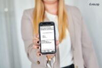 Frau zeigt App zur digitalen Postbox auf ihre Handy