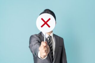 Personaler hält ein rundes Schild mit einem x hoch und signalisiert eine Jobabsage