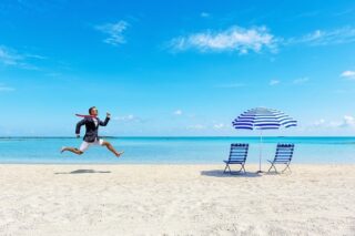 Mann rennt im Business-Anzeig über den Strand, vom Büro in den Urlaub