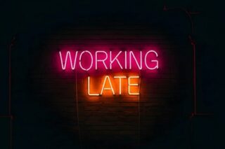 Working late steht in Neonfarben auf schwarzem Untergrund