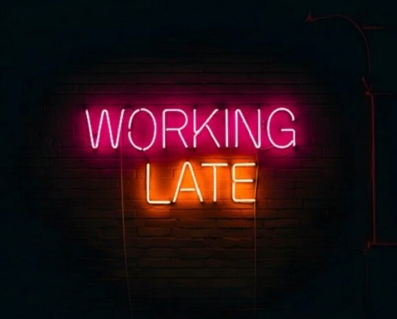 Working late steht in Neonfarben auf schwarzem Untergrund