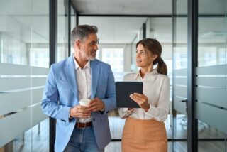 Mann und Frau gehen nebeneinander im Büro entlang.