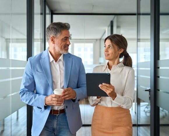 Mann und Frau gehen nebeneinander im Büro entlang.