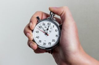 Mensch hält Stoppuhr in der Hand und stoppt das Tempo.