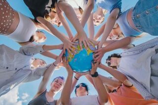Menschen halten zusammen Weltkugel hoch und stehen für ein internationales Team