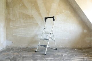Leiter in einem leeren Raum, der renoviert werden muss, steht für Neuanfang