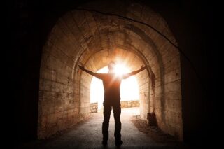 Mann steht vor dem Licht am Ende des Tunnels