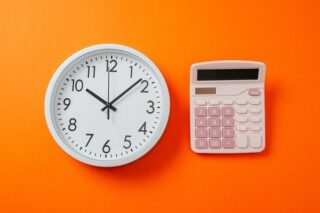 Uhr neben Taschenrechner symbolisieren Arbeitszeit