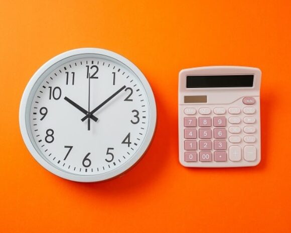 Uhr neben Taschenrechner symbolisieren Arbeitszeit