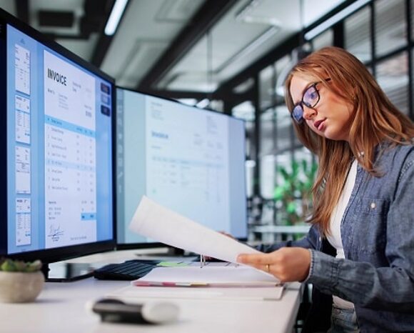 Frau sitzt am Schreibtisch und erledigt die Entgeltabrechnung.