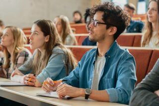 Junge Studenten hören im Hörsaal zu