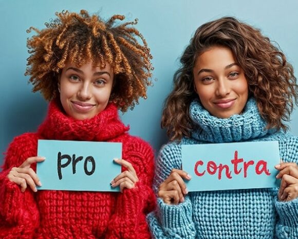 Zwei Frauen in dicken Pullis halten Schilder hoch mit Pro und Contra.