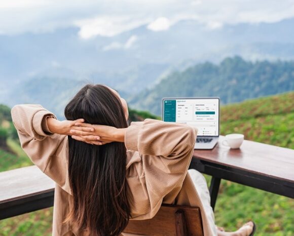 Junge Frau arbeitet am Laptop und schaut auf die Berge.