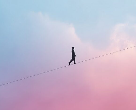 Mensch balanciert vor rosa-blauem Himmel über Seil