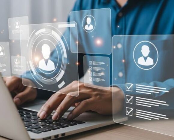 Person arbeitet an einem Laptop mit schwebenden digitalen Symbolen und Profil-Icons, die Personal- oder Payroll-Daten darstellen. Das Bild steht sinnbildlich für moderne, automatisierte Entgeltabrechnung und digitale HR-Prozesse.