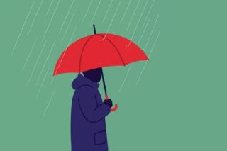 Mann mit rotem Regenschirm steht im Regen