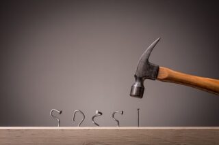 Hammer schlägt Nägel schief ein