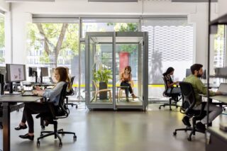 Mitarbeitende arbeiten in einem Büro mit verschiedenen Arbeitsmöglichkeiten und -plätzen