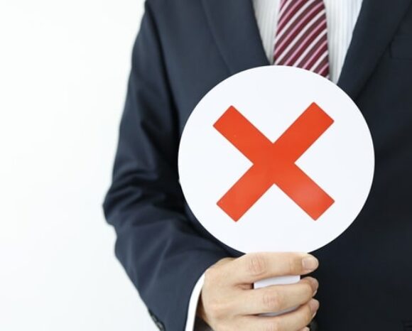 Ein Mann hält rundes Schild mit x hoch, was Ablehnung symbolisiert.