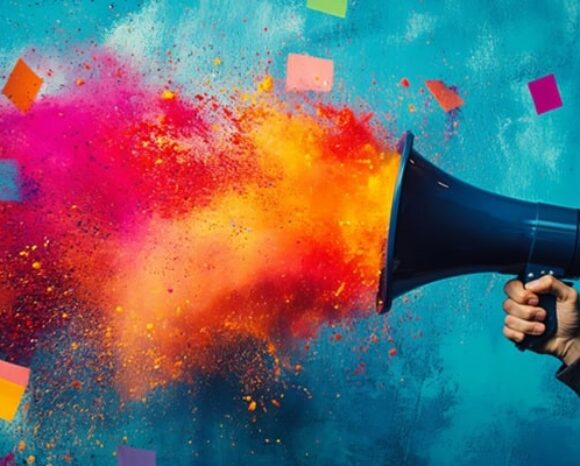 Ein Mensch hält ein Megafon, aus dem bunter Farbstaub kommt.