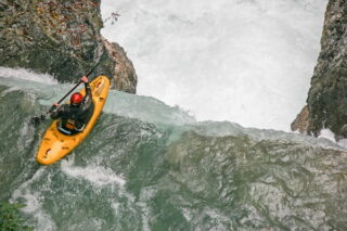 Kanufahrer überlegt, ob er Wasserfall hinterfahren soll
