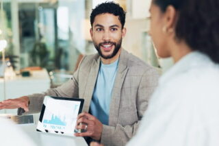 Mann und Frau reden über Zahlen auf einem Tablet