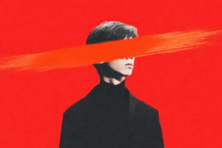 Mann im dunklen Anzug vor rotem Hintergrund, wobei Augenpartie durchgestrichen ist