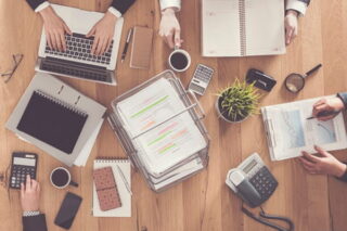 Blick von oben auf Mitarbeitende im Büro, die zusammen arbeiten