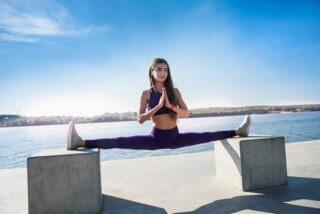 Frau macht einen Spagat über zwei Betonklötze