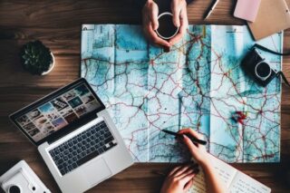 Zwei Menschen planen Urlaub zusammen mit einer Karte und Laptop