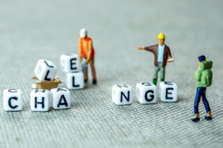 Männchen bauen Klötze, auf denen Challenge steht, in Change um