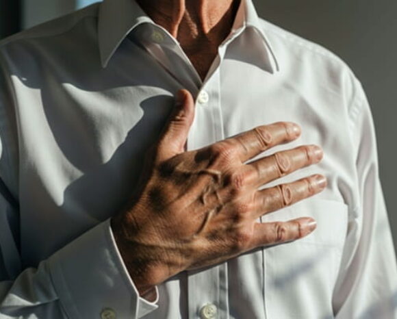 Mann im weißen Hemd hält sich Hand ans Herz