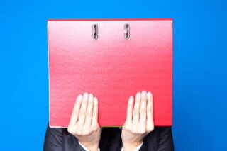 Mensch hält sich Ordner vors Gesicht, symbolisiert Sonderkündigungsschutz