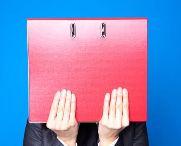 Mensch hält sich Ordner vors Gesicht, symbolisiert Sonderkündigungsschutz