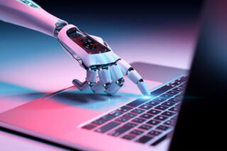 Hand, die KI darstellen soll, tippt auf eine Taste am Laptop