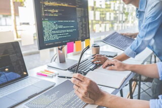 Zwei Kollegen testen am Bildschirm HR-Software