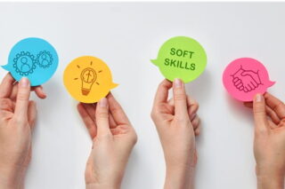 Hände halten verschiedene Symbole zu Soft Skills hoch