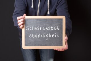 Mann hält Tafel hoch, auf der Scheinselbstständigkeit steht