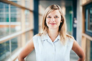 Junge blonde Frau schaut lächelnd in Kamera