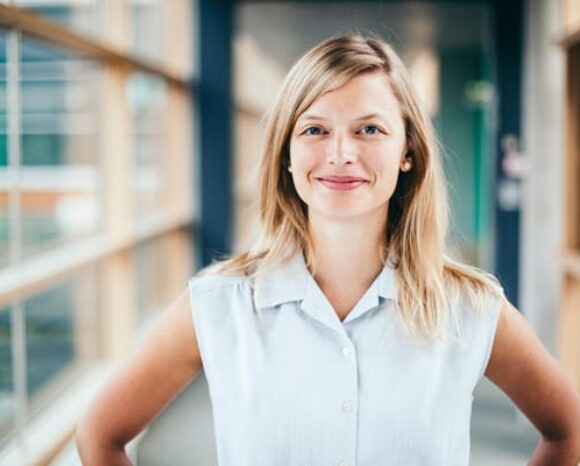 Junge blonde Frau schaut lächelnd in Kamera
