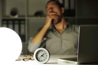 Mann arbeitet nachts am Laptop und gähnt