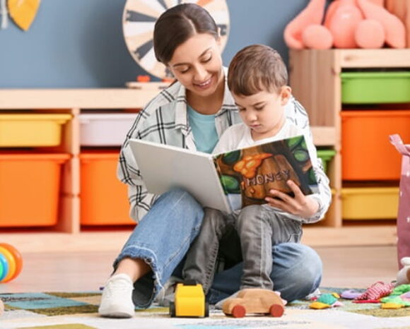 Frau liest im Kindergarten einem Jungen ein Buch vor