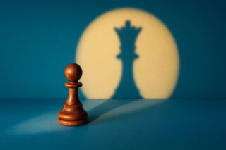Schachfiguren: Bauer wird angestrahlt, in seinem Schatten zeigt sich, dass er der König ist
