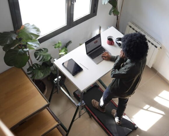 Frau arbeitet am Laptop und läuft auf Laufband